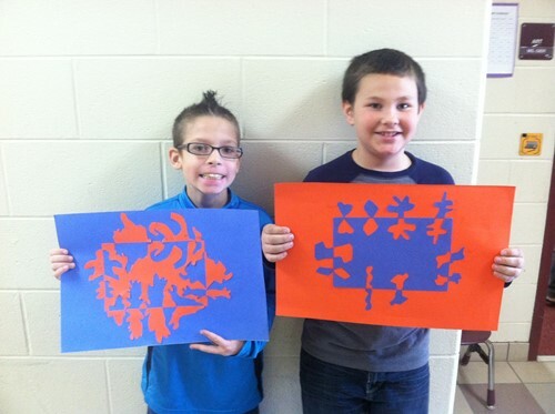 Two kids holding up artwork