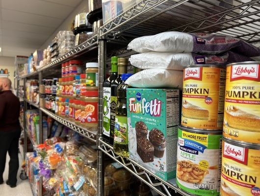 Shelf shows items in food pantry, like cake mix, canned goods, oils, and peanut butter.