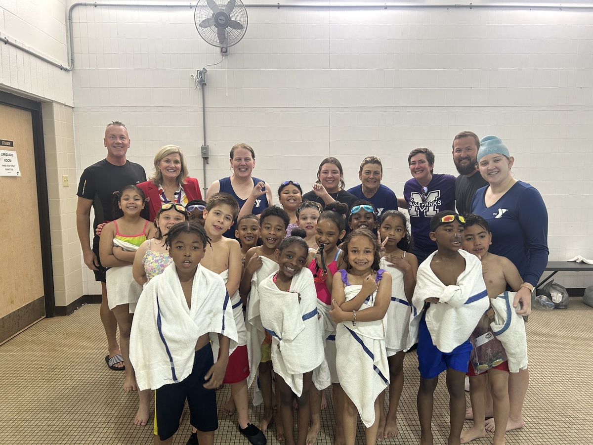 Photo shows adults and students posing next to YMCA pool