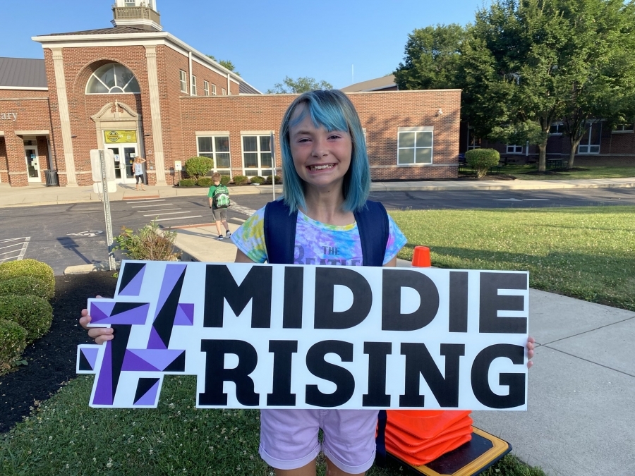 Girl with blue hair holding #MiddieRising sign