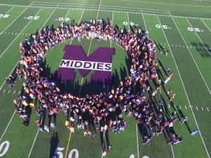 people on football field surrounding Middies M logo